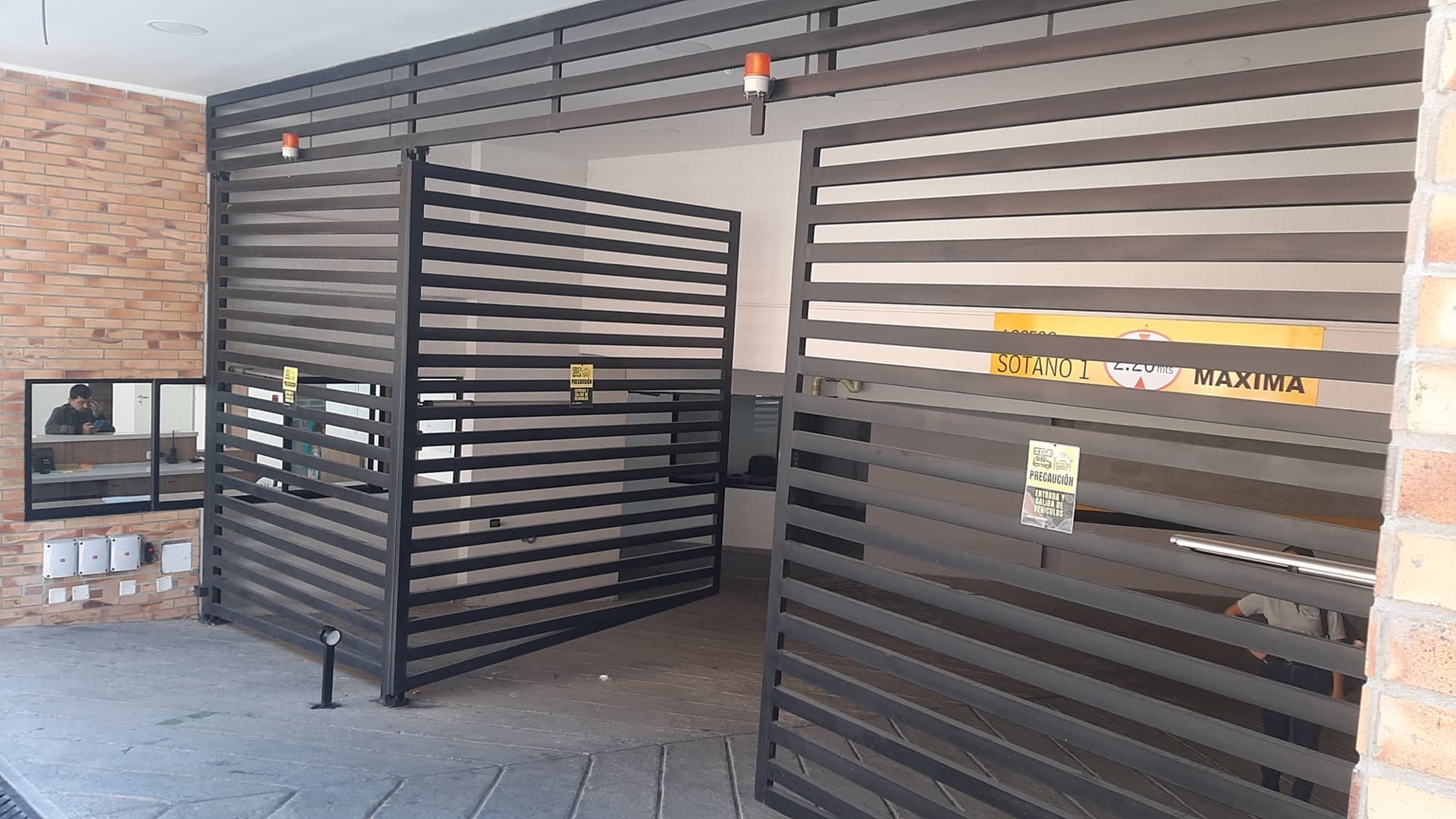 Acceso vehicular de un edificio con dos hojas automatizadas y balizas